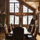 Big Sky Elk & Mule Deer Antler Chandelier hanging in a log cabin dining room with vaulted windows