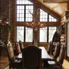 Big Sky Elk & Mule Deer Antler Chandelier hanging in a log cabin dining room with vaulted windows