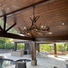 Big Sky Elk & Mule Deer Antler Chandelier hanging under a wood pergola on an outdoor patio