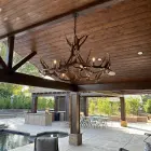 Big Sky Elk & Mule Deer Antler Chandelier hanging under a wood pergola on an outdoor patio