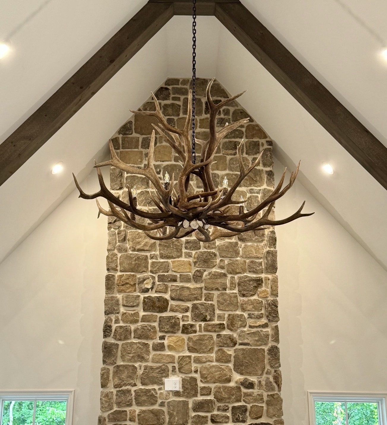 Yellowstone Elk Antler Chandelier in a bleached white finish, hanging from a vaulted white ceiling with dark wood beams