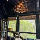 Deerlodge mule deer antler chandelier installed in a navy blue paneled sitting room with woven window shades