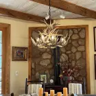 Two Tier Whitetail Antler Chandelier installed in a dining room with exposed candle-style bulbs
