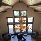 Selway 2-tier elk antler chandelier hanging in a gable-end vaulted room with tall windows