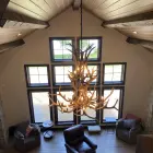 Selway 2-tier elk antler chandelier hanging in a gable-end vaulted room with tall windows