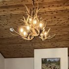Aspen 2-tier mule deer antler chandelier in natural finish hanging from a rustic wood plank ceiling