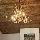 Aspen 2-tier mule deer antler chandelier in natural finish hanging from a rustic wood plank ceiling