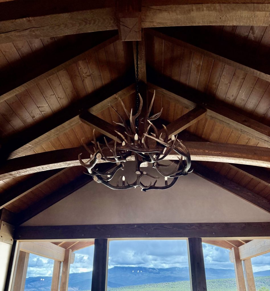Big Sky elk and mule deer antler chandelier hanging from vaulted timber trusses at Spirit Ranch in Montrose, Colorado, with mountain views