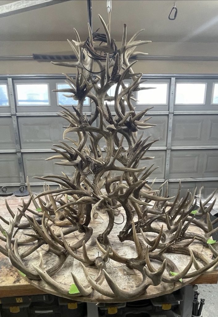 Six-tier whitetail antler chandelier with a wider outer ring, the added antlers marked with green tape for customer approval