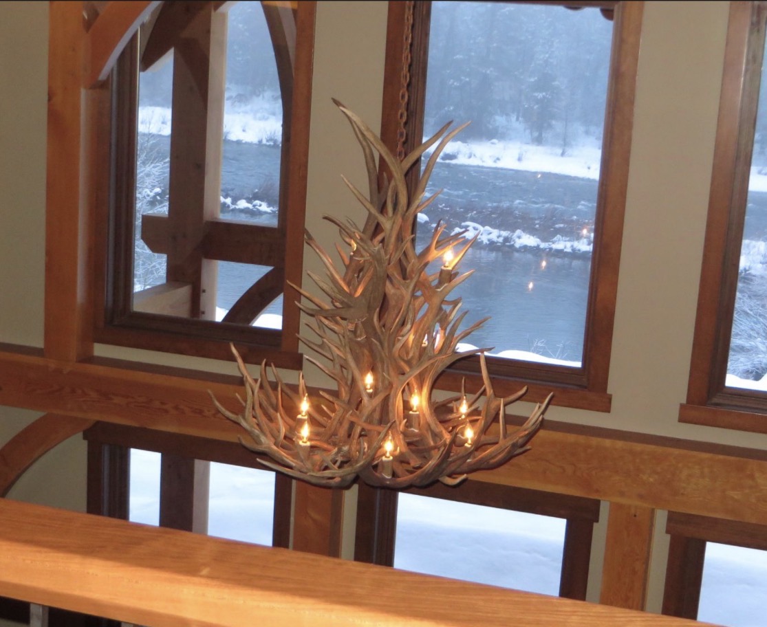 Salish Elk & Mule Deer Antler Chandelier illuminated above a great room with a river view