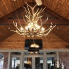 Snowcrest Elk Antler Chandelier lit in a great room near a fireplace