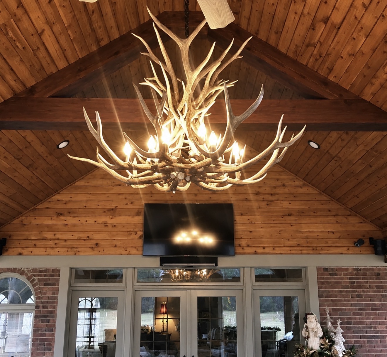 Snowcrest Elk Antler Chandelier lit in a great room near a fireplace