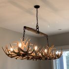 Luxury whitetail antler rectangular chandelier installed over a kitchen island, lit