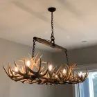 Roundup rectangular antler chandelier installed over a kitchen island, lit, showing its elongated span