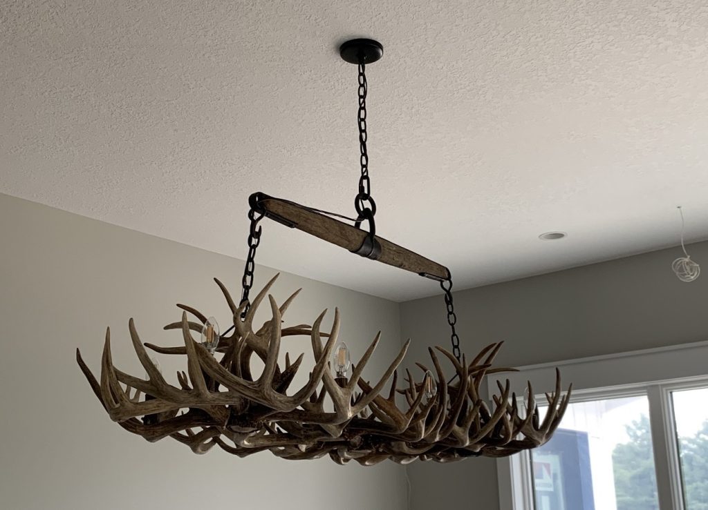 Eight-light rectangular whitetail shed antler chandelier hanging from an antique yoke