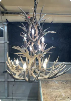Two-tier antler chandelier with candle-style bulbs lit, hanging on display