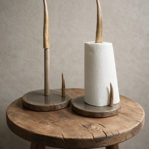 Two antler paper towel holders, one with a gray base and one with a brown wood base holding a roll