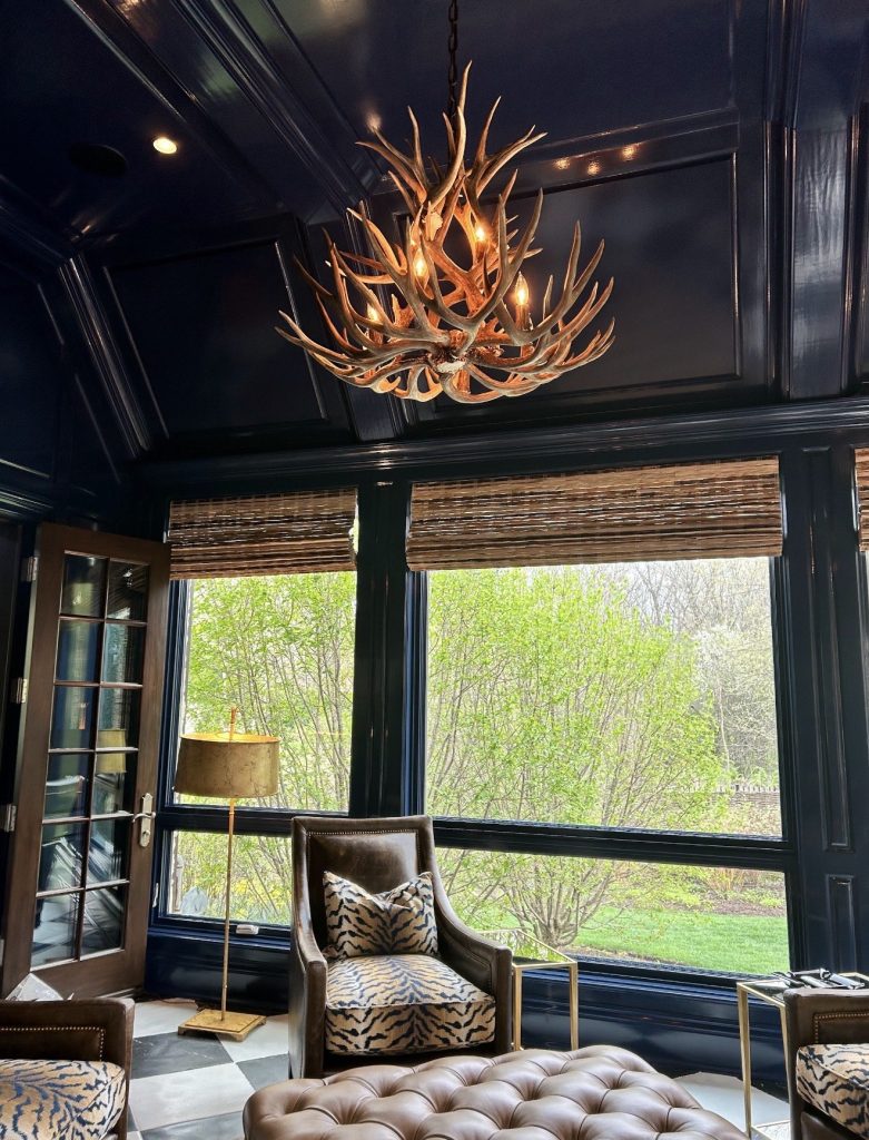 Mule deer antler chandelier lit against coffered navy ceiling