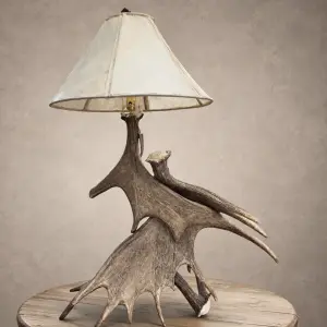 Kenai moose antler table lamp with stacked moose antler paddles and a laced rawhide shade on a wood side table