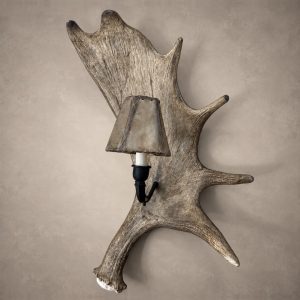 Denali moose antler wall sconce, a single moose antler paddle with a black iron arm and rawhide-style shade, mounted on a wall