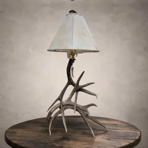 Mule deer antler table lamp – Madison: real mule deer antler base with a rawhide shade and antler-tip pull chain, on a wood side table