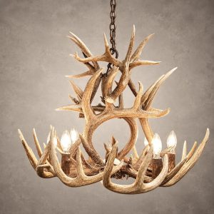 Two Tier Whitetail antler chandelier lit with candle-style bulbs, an upper tier of crossed whitetail antler above a lower ring of antler and lights, hanging from an iron chain