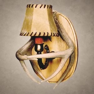Whitetail antler wall sconce – Kootenai: crossed whitetail deer antlers around a single light with a laced rawhide shade, on the standard wood back plate