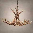 Wilderness elk antler chandelier lit with candle-style bulbs, hanging from a black chain against a textured gray backdrop
