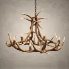 Yellowstone elk antler chandelier lit with candle-style bulbs, a tall crossed-antler center above a wide elk antler ring, hanging from a black chain