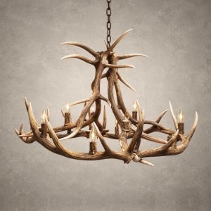 Yellowstone elk antler chandelier lit with candle-style bulbs, a tall crossed-antler center above a wide elk antler ring, hanging from a black chain