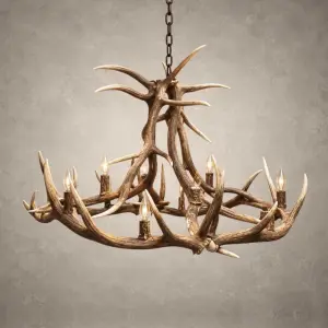 Yellowstone elk antler chandelier lit with candle-style bulbs, a tall crossed-antler center above a wide elk antler ring, hanging from a black chain